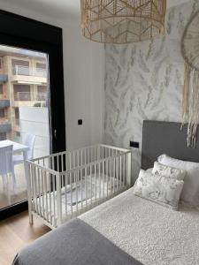 a bedroom with a crib and a window with a table at Precioso apartamento con terraza y piscina en Portonovo-Sanxenxo in Portonovo