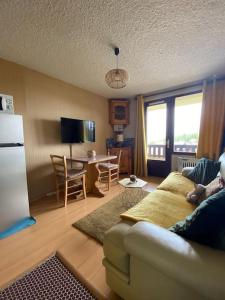 a living room with a couch and a kitchen with a table at Laye station - les Arolles A - 4 personnes in Laye