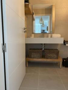 uma casa de banho com um lavatório e um espelho em Precioso apartamento con terraza y piscina en Portonovo-Sanxenxo em Portonovo