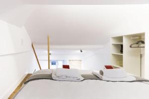 a white room with a bed with two pillows at CHARMING SANTOS by Homing in Lisbon