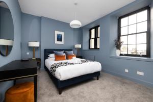 a bedroom with blue walls and a bed with orange pillows at ALTIDO Stylish 2-bed flat in New Town in Edinburgh