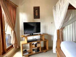 a television on a stand in a room with a bed at Villa Agung Khalia Ubud in Ubud
