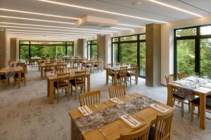 restauracja ze stołami, krzesłami i oknami w obiekcie Sporthotel Olympia w mieście Stachy