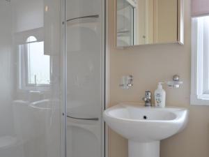 a white bathroom with a sink and a shower at Neuadd Wen Cottages - Porthdy Crey R Wen in Llanfachraeth