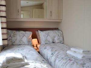 een slaapkamer met 2 bedden, een lamp en een spiegel bij Neuadd Wen Cottages - Porthdy Crey R Wen in Llanfachraeth
