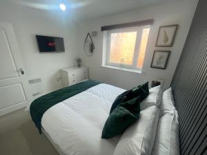 a bedroom with a large white bed with green pillows at Grand Station Suite in Wolverhampton
