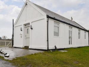 a white building with a door and a grass yard at Craig Hall in Drummore