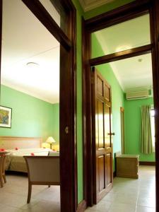 a room with green walls and a bedroom with a bed at Gregoire's Apartment in La Digue