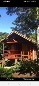 Casa de madera con porche y árbol en Pousada Recanto Afetivo en Trindade