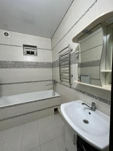 bagno con lavandino, vasca e specchio di MINI HOTEL COMFORT a Shymkent