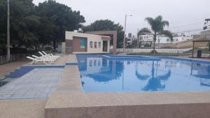 ein Pool mit zwei Stühlen und ein Gebäude in der Unterkunft Relax Habitación Privada in Manta