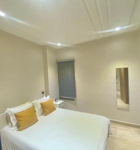 een slaapkamer met een wit bed met gele kussens bij Superbe appartement très bien situé in Casablanca