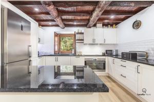 a kitchen with white cabinets and a stainless steel refrigerator at Casa do Monte Locally Yours in Caminha