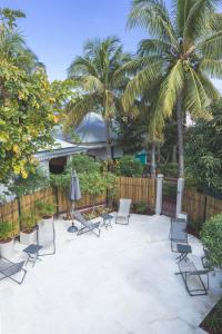 a patio with chairs and palm trees and a fence at Ilet du Lagon in La Saline les Bains