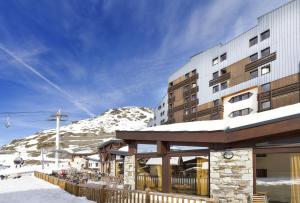 a building with a snow covered mountain in the background at Hôtel Club mmv Les Arolles **** in Val Thorens