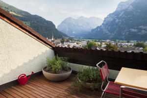 einen Balkon mit einem Tisch, Stühlen und Bergen in der Unterkunft Kerenzer15 - The Studio in Mollis