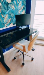 een bureau met een computermonitor en een stoel bij VogelsNest in Neurenberg
