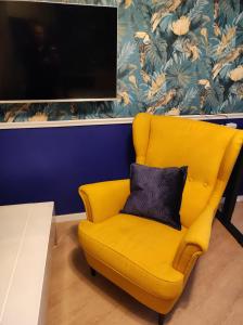 a yellow chair with a black pillow in a room at VogelsNest in Nürnberg