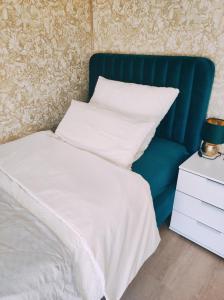 a bed with a blue headboard and white sheets and pillows at VogelsNest in Nürnberg