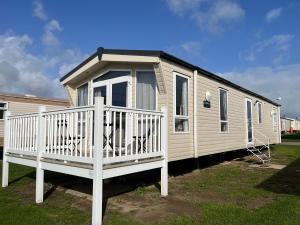 a mobile home with a white railing and a porch at Fulmar 16, Scratby - California Cliffs, Parkdean, sleeps 6, pet friendly - 2 minutes from the beach! in Scratby