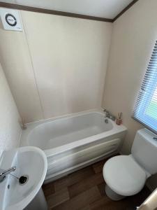 a bathroom with a tub and a toilet and a sink at Fulmar 16, Scratby - California Cliffs, Parkdean, sleeps 6, pet friendly - 2 minutes from the beach! in Scratby