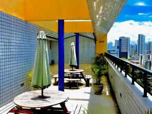 a balcony with tables and umbrellas on a building at Flat Boa Viagem luxo in Recife