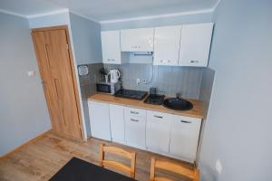 una pequeña cocina con armarios blancos y fregadero en Apartament Słoneczna Centrum en Zakopane