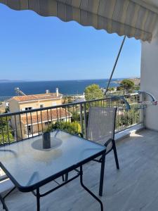 einen Tisch und einen Stuhl auf einem Balkon mit Meerblick in der Unterkunft Sunrise pearl in Attika Riviera apt and Parking in Rafina