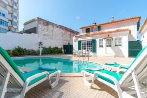 a villa with a swimming pool and two lawn chairs at Villa Praia Nova in Almada