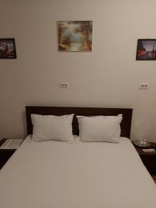 a bedroom with a large bed with two pictures on the wall at Casa Stefan Galati in Galaţi
