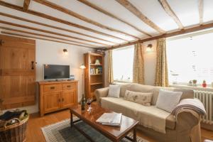 a living room with a couch and a tv at Flaxen Cottage, Heveningham in Heveningham