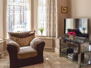 a living room with a chair and a television at The Terrace in Great Yarmouth