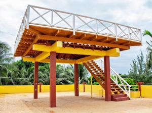 a large wooden structure with a staircase in front of a yellow wall at Sunshine House in San Pedro