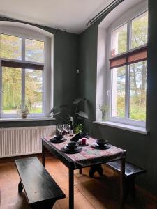 a dining room with a table and two windows at Apartament z kominkiem in Piechowice