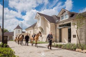 a group of people walking horses down a street at Le Grand Pavillon Chantilly in Chantilly