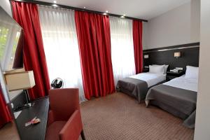 una habitación de hotel con 2 camas y cortinas rojas en Delta In, en Dzierżoniów