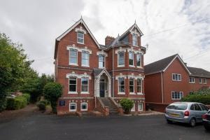 a large red brick house with a car parked in front at Stylish Central 2 Bedroom Apartment in Hereford