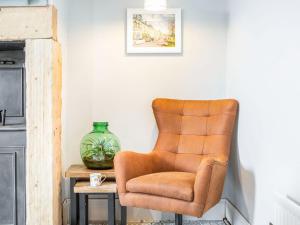 una silla marrón sentada junto a una mesa con un jarrón en Carven House, en Rothbury