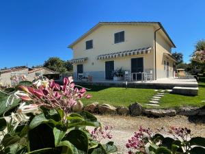 una gran casa blanca con un patio con flores en Hotel Poggio Bertino, en Montemerano