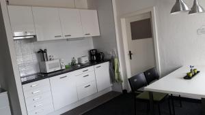 una cocina con armarios blancos y una mesa con sillas. en Rivierzicht, en Neuhausen