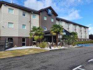 un bâtiment d'hôtel avec des palmiers devant lui dans l'établissement Hotel Ibis Budget Deauville, à Deauville