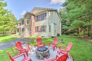 a group of red chairs around a fire pit in front of a house at Gorgeous Pocono Summit Retreat with Game Room! in Pocono Summit