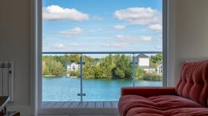 a living room with a view of a lake through a window at Gorgeous 4 bedroom Cotswolds home with lake view in South Cerney