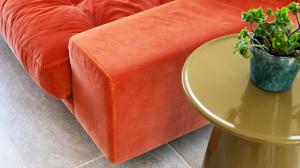 an orange couch with a table and a potted plant at Gorgeous 4 bedroom Cotswolds home with lake view in South Cerney