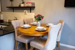 a wooden table with chairs and a vase of flowers on it at Stylish Central 2 Bedroom Apartment in Hereford