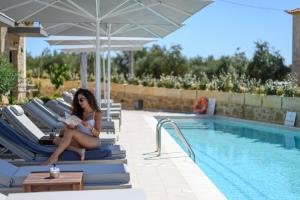 a woman sitting on lounge chairs next to a swimming pool at Kannas Luxury Suites Mani in Stoupa