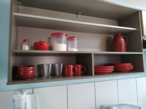 un estante de cocina con tazas rojas y platos. en Apto em Curitiba perto de tudo en Curitiba