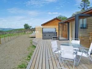 a wooden deck with a table and chairs on it at Sweet Meadow Lodge in Llandrindod Wells