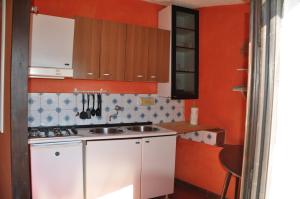 a small kitchen with orange walls and white cabinets at Cotetonda - Appartamento Taccola in Marciana Marina