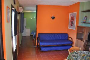 una camera con un divano blu e una parete arancione di Cotetonda - Appartamento Taccola a Marciana Marina